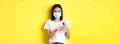 科维德健康护理流感大流行概念可爱的亚洲女人医疗面具手洗手液消毒棕榈站黄色的背景