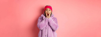 时尚概念时尚的亚洲女人惊讶相机成熟的女紫色的外套头巾惊讶相机检查促销活动粉红色的背景
