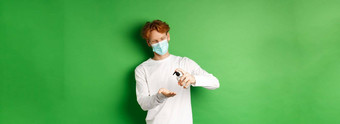 科维德病毒社会距离概念红色头发的人的家伙医疗面具手洗手液微笑<strong>预防措施</strong>冠状病毒绿色背景
