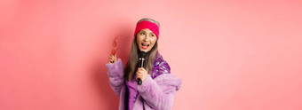 华丽的亚洲高级女人唱歌卡拉ok小执行首歌快乐站粉红色的背景