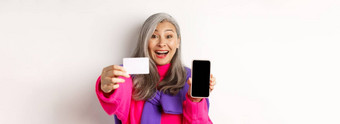 在线购物特写镜头时尚的朝鲜文高级女人显示空移动屏幕塑料信贷卡微笑快乐站白色背景