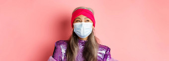科维德病毒时尚概念特写镜头快乐时尚的亚洲高级女人医疗面具笑左快乐的站粉红色的背景