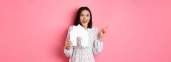 真正的房地产兴奋亚洲女人显示纸房子模型指出左复制空间站粉红色的背景