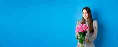情人节一天概念浪漫的女孩衣服快乐花微笑花束粉红色的玫瑰站蓝色的背景