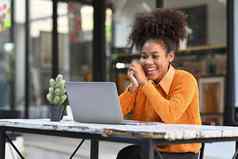 快乐的非洲美国女人视频调用看在线网络研讨会移动PC坐着户外咖啡馆
