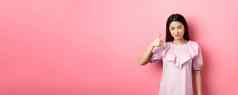 微笑亚洲女孩显示拇指批准赞美好选择推荐产品站粉红色的背景