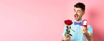 情人节一天有趣的的家伙使建议眨眼结婚显示订婚环红色的玫瑰站粉红色的背景