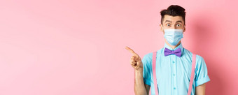 科维德流感大流行健康概念图像惊讶的家伙医疗面具促销交易指出手指左好奇的站粉红色的背景