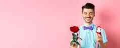 情人节一天可爱的的男朋友使婚礼建议显示订婚环小盒子红色的玫瑰表达爱站粉红色的背景