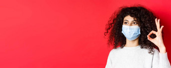科维德健康概念图像年轻的女人医疗面具批准促销显示手势空空间站红色的背景