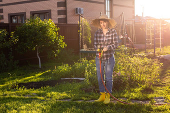 高加索人女人园丁工作衣服浇水床蔬菜花园阳光明媚的温暖的夏天一天概念工作花园农场