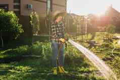 快乐女人园丁工作衣服浇水床蔬菜花园阳光明媚的温暖的夏天一天概念工作蔬菜花园农场