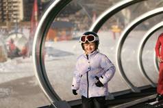 女孩滑雪板站地毯滑雪电梯玻璃隧道