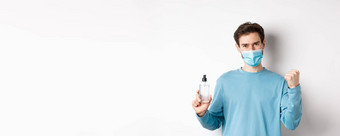 科维德健康检疫概念快乐的男人。脸面具庆祝显示拳头泵瓶手洗手液战斗细菌白色背景