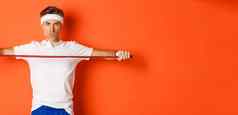 概念锻炼健身房生活方式自信中年健身的家伙持有伸展运动绳子练习站橙色背景