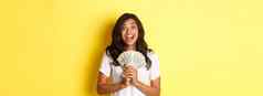 图像美丽的兴奋非裔美国人女孩赢得钱奖微笑持有现金相机站黄色的背景