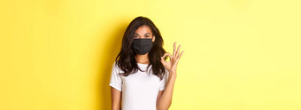 概念冠状病毒流感大流行生活方式肖像微笑非裔美国人女人脸面具显示标志批准推荐保证黄色的背景