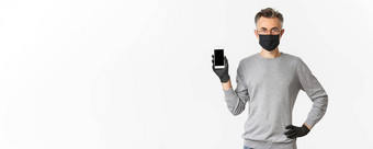 概念科维德社会距离生活方式图像自信中年男人。眼镜医疗面具手套显示智能手机屏幕演示应用程序