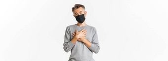 科维德流感大流行社会距离概念图像感激中年男人。黑色的医疗面具持有手心表达感激之情站白色背景