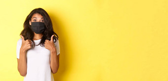 概念冠状病毒流感大流行生活方式肖像美丽的非裔美国人女孩黑色的脸面具显示竖起大拇指批准好黄色的背景