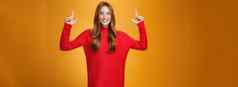 热情的兴奋精力充沛红色头发的人女红色的温暖的毛衣指出其三手微笑广泛的激动太棒了促销活动感觉惊讶橙色背景