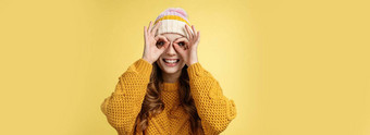 惊讶逗乐感兴趣有吸引力的年轻的欧洲女人穿灯芯绒他针织毛衣扩大眼睛好奇的显示双筒望远镜眼镜使手指微笑惊讶黄色的背景