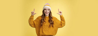 友好的迷人的精力充沛年轻的女人正式的礼服时尚的他毛衣有趣的介绍促销活动指出提高了指数手指显示前广告微笑幸福的黄色的背景