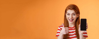 快乐的自信的红色头发的人女人推荐智能手机应用程序显示电话显示翘拇指批准标志微笑广泛的建议好在线购买移动广告