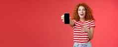 太棒了智能手机深刻的印象兴奋好看的女爱数字创新红色头发的人女孩卷曲的发型显示电话屏幕指出显示促进很酷的应用程序