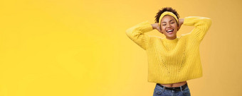 无忧无虑的快乐的幸运的非裔美国人女学生毛衣头巾躺回来手头放松令人心寒的构成休假日周末微笑广泛的笑黄色的背景