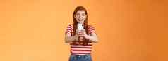 逗乐兴奋红色头发的人女记录视频激动著名的人微笑惊讶持有智能手机采取图片旅游喜欢旅行拍摄夏天旅程橙色背景