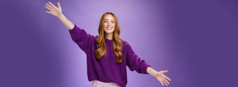 女孩拉<strong>伸手</strong>横盘整理问候朋友给温暖的拥抱微笑广泛的相机站快乐的想<strong>要</strong>拥抱紫色的背景穿紫罗兰色的毛衣裤子