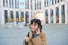 细胞技术年轻的朝鲜文女人会谈移动电话使电话调用首页走街城市中心电话谈话