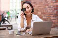快乐年轻的亚洲女坐着移动PC显示信贷卡支付账单在线购物互联网坐着咖啡馆咖啡