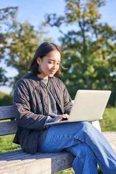 年轻的亚洲女人工作远程自由女孩坐在公园移动PC工作在户外