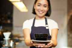 肖像微笑亚洲女孩咖啡师女服务员咖啡馆统一的给杯咖啡准备喝客户端友好的
