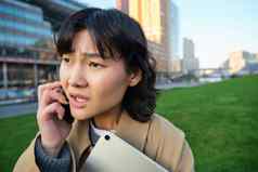 关闭肖像年轻的亚洲女人会谈移动电话有关脸听到坏新闻电话谈话走大学平板电脑