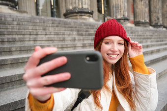 年轻的红色头发的人旅游需要自拍前面博物馆楼梯持有智能手机移动相机使照片电话