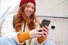 移动手机人年轻的时尚的红色头发的人女孩坐在楼梯电话智能手机应用程序读取smth在线