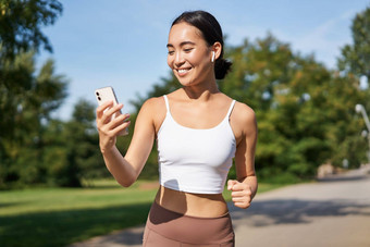 健身女人水瓶智能<strong>手机</strong>慢跑公园微笑移动电话应用程序检查<strong>体育运动</strong>应用程序