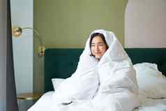 舒适的早晨快乐亚洲女孩感觉温暖的床上涵盖了舒适的羽绒被卧室舒适的保持酒店房间