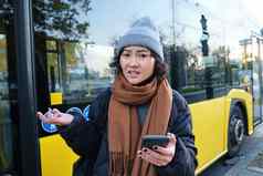 肖像困惑年轻的女人智能手机应用程序震惊了失望脸耸了耸肩肩膀读取坏新闻站公共汽车停止公共运输