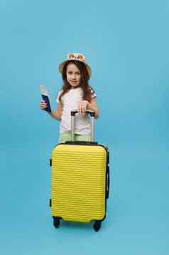 完整的长度女孩夏天穿飞行票站黄色的手提箱孤立的蓝色的背景