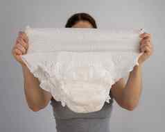 高加索人女人持有成人尿布检查强度白色背景