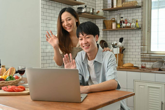 图像可爱的亚洲夫妇使视频调用朋友家庭<strong>移动</strong>PC电脑坐着舒适的<strong>厨房</strong>