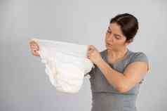 高加索人女人持有成人尿布检查强度白色背景