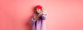 亚洲高级女模型时尚的紫色的冬天外套站受害者构成扩展手停止手势恳求怜悯站粉红色的背景