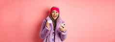 在线购物时尚概念快乐亚洲女检查互联网促销活动持有信贷卡智能手机粉红色的背景