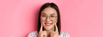 美概念头像可爱的亚洲女孩时尚的眼镜微笑戳脸颊显示可爱的酒窝站粉红色的背景