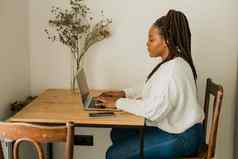 快乐的非洲美国女人移动PC坐着椅子生活房间学生视频调用工作首页概念